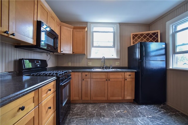 kitchen with a sink, black appliances, wood walls, dark countertops, and marble finish floor