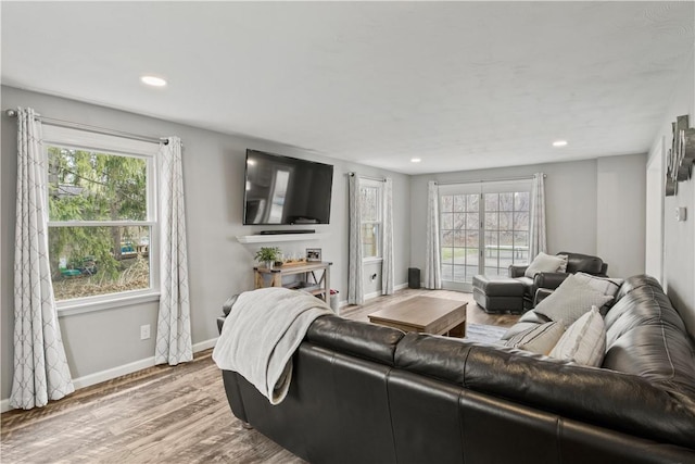 living area with recessed lighting, wood finished floors, baseboards, and a wealth of natural light