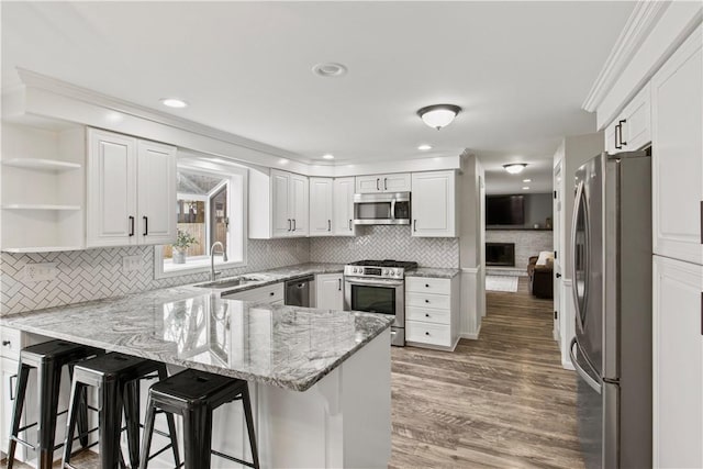 kitchen featuring a sink, stainless steel appliances, a peninsula, and white cabinets