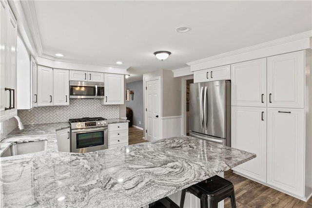 kitchen featuring light stone countertops, a peninsula, a sink, stainless steel appliances, and dark wood-type flooring