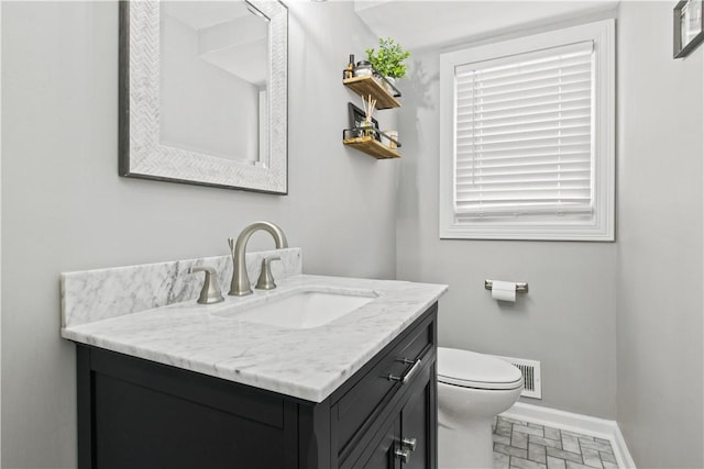 half bathroom featuring visible vents, toilet, vanity, and baseboards