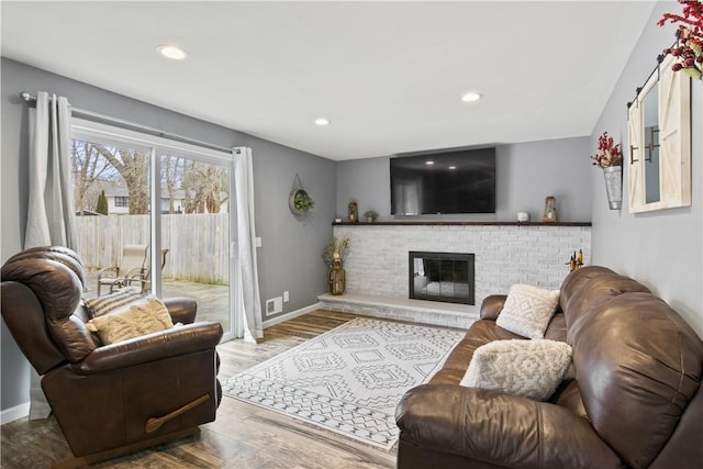 living area featuring wood finished floors, visible vents, baseboards, recessed lighting, and a fireplace