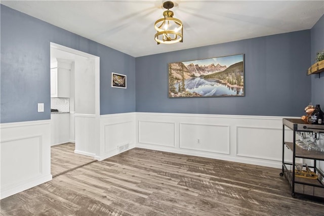 dining area with visible vents, wood finished floors, wainscoting, and a chandelier