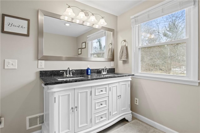 full bathroom featuring a sink, visible vents, baseboards, and double vanity