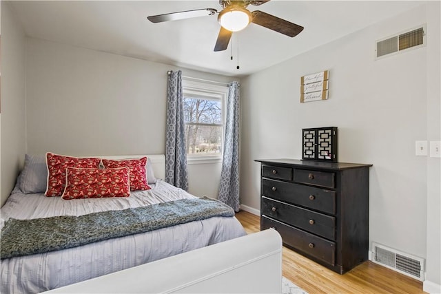 bedroom featuring light wood finished floors, visible vents, baseboards, and a ceiling fan