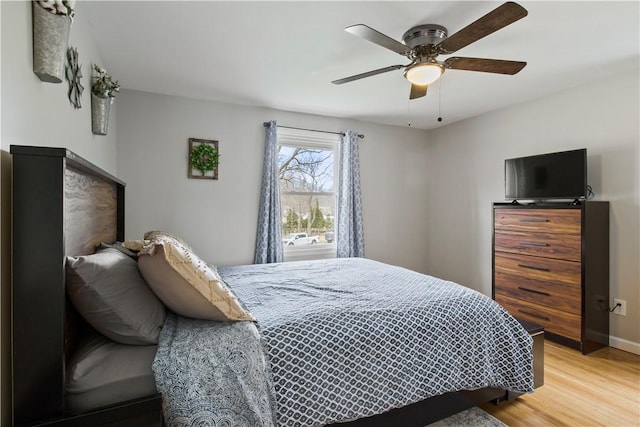 bedroom with a ceiling fan, light wood-style floors, and baseboards