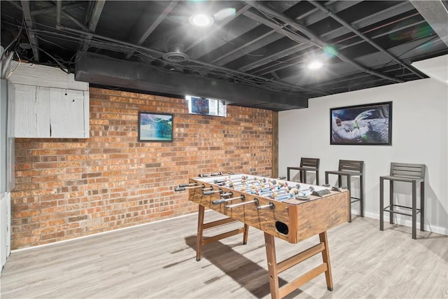 rec room with brick wall, baseboards, and light wood-style floors