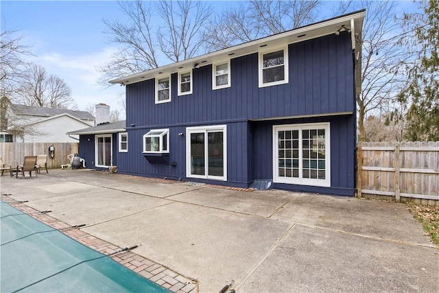 back of house with a fenced backyard, a fenced in pool, a chimney, and a patio