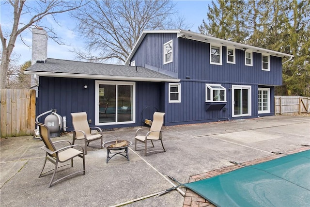 rear view of property with a patio, an outdoor fire pit, a chimney, and fence