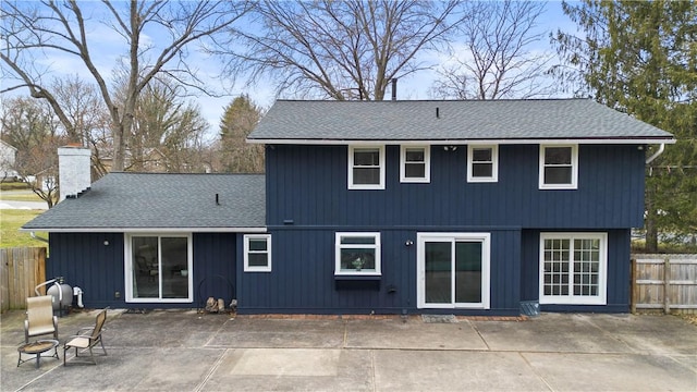 back of house featuring a shingled roof, a patio area, fence, and a chimney