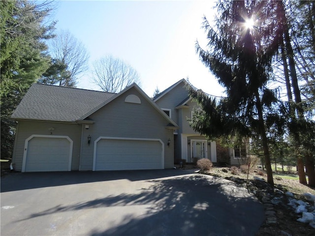 view of front of property with an attached garage, a shingled roof, and driveway