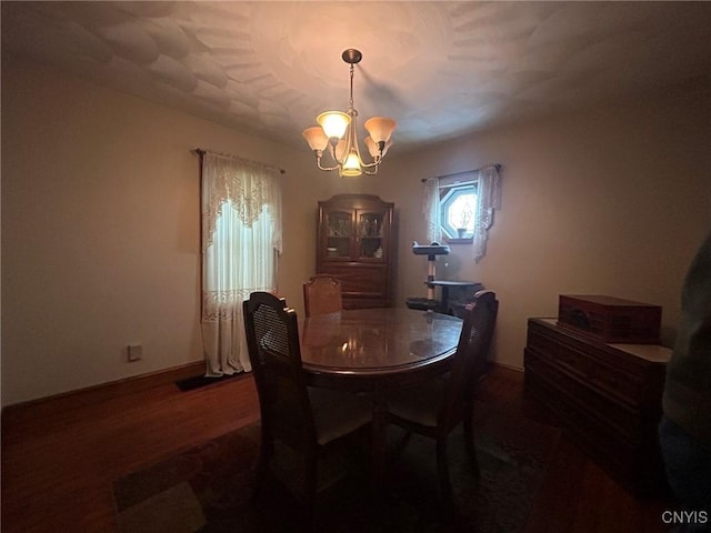 dining area featuring baseboards, an inviting chandelier, and wood finished floors