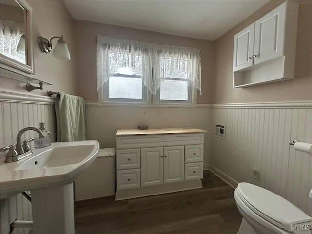 bathroom featuring a sink, toilet, wood finished floors, and wainscoting