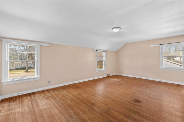 spare room featuring visible vents, baseboards, lofted ceiling, and wood finished floors