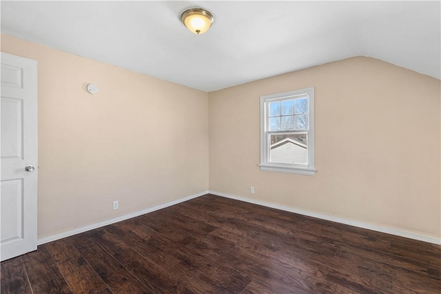 empty room featuring lofted ceiling, wood finished floors, and baseboards