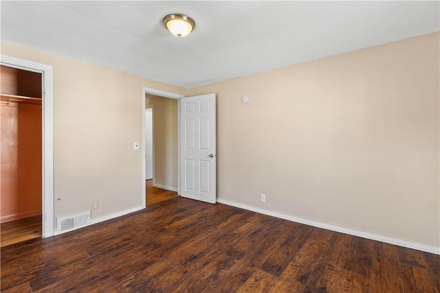 unfurnished bedroom featuring visible vents, baseboards, a closet, and dark wood-style flooring