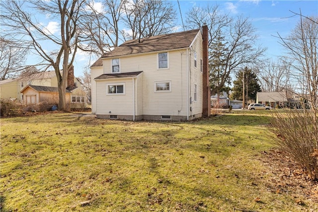 rear view of house featuring a yard and a chimney