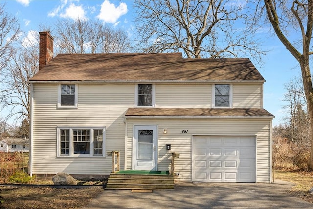 traditional-style home with driveway, a chimney, and a garage