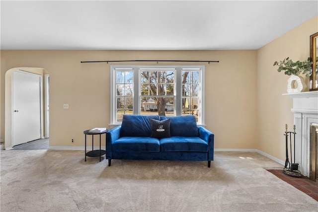 sitting room with arched walkways, a fireplace with flush hearth, baseboards, and carpet