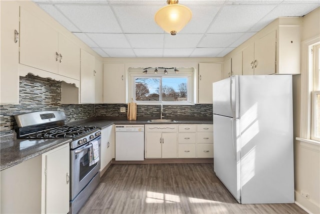 kitchen with a sink, light wood-type flooring, white appliances, and dark countertops