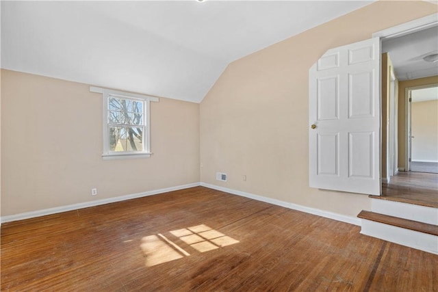 interior space featuring visible vents, baseboards, wood finished floors, and vaulted ceiling