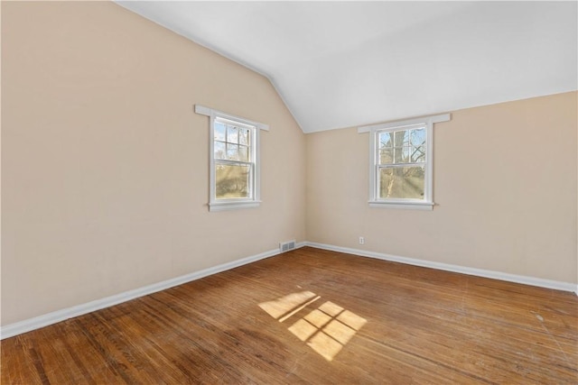 unfurnished room with a healthy amount of sunlight, wood finished floors, baseboards, and vaulted ceiling