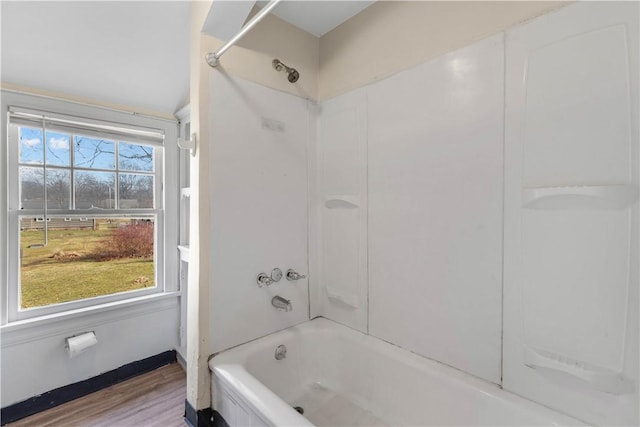 full bathroom featuring shower / tub combination, wood finished floors, baseboards, and a wealth of natural light