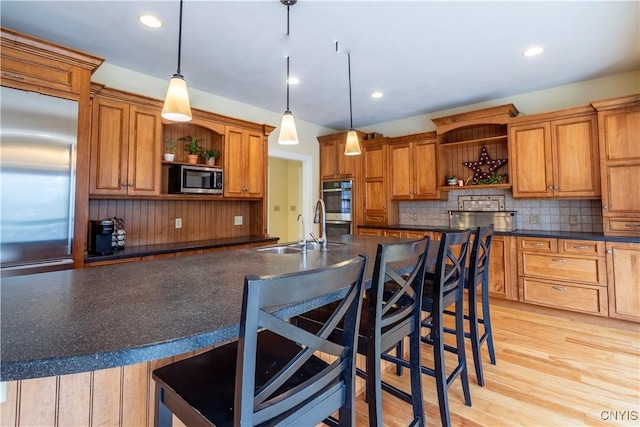 kitchen with dark countertops, backsplash, open shelves, stainless steel appliances, and a sink