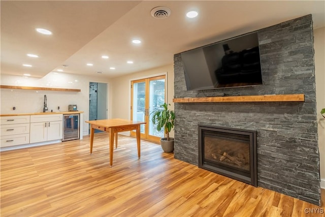 dining space featuring beverage cooler, visible vents, a fireplace, and light wood-type flooring