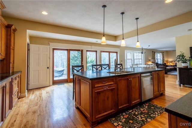 kitchen featuring a kitchen island with sink, a sink, hanging light fixtures, light wood-style floors, and open floor plan