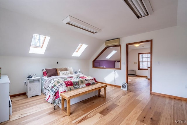 bedroom with baseboards, a wall mounted air conditioner, light wood-style floors, and vaulted ceiling