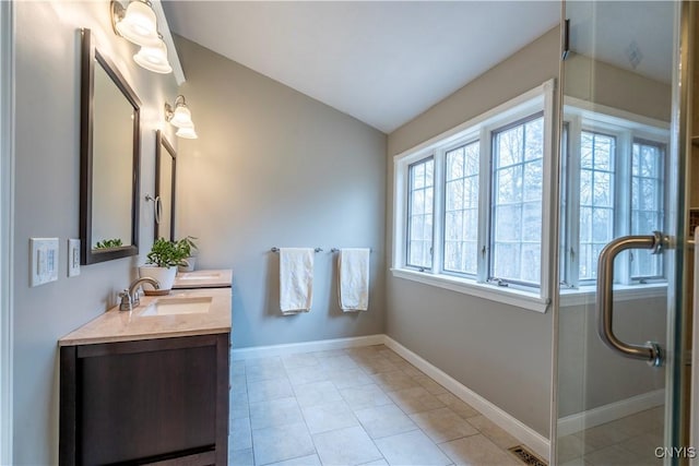 bathroom with baseboards, visible vents, lofted ceiling, double vanity, and a sink