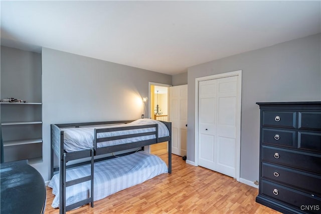 bedroom with baseboards, a closet, and light wood finished floors