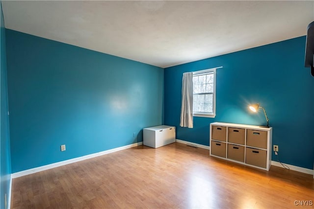 spare room with visible vents, baseboards, and wood finished floors