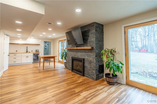 living room featuring visible vents, recessed lighting, wine cooler, light wood-style floors, and a fireplace