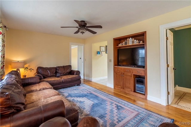 living area featuring baseboards, a ceiling fan, and light wood finished floors