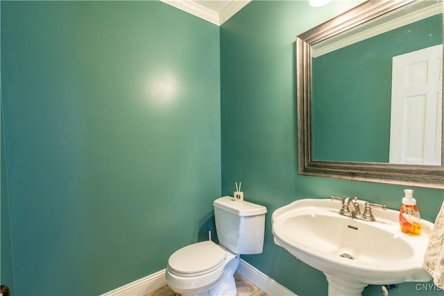 half bath featuring baseboards, a sink, crown molding, toilet, and tile patterned floors