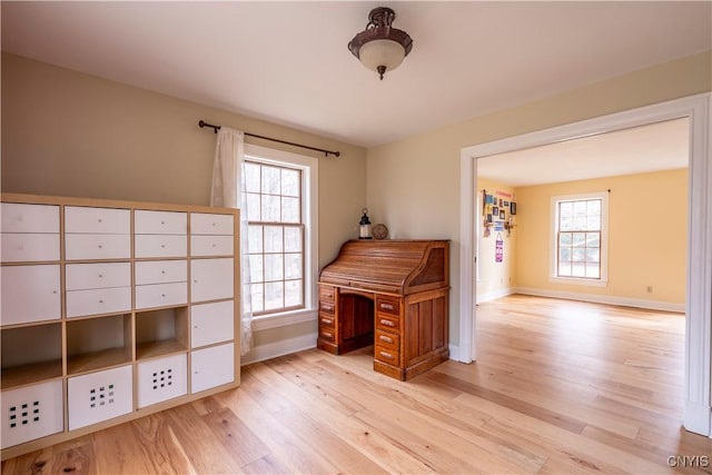 home office featuring baseboards, light wood-type flooring, and a wealth of natural light