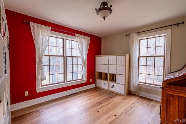 unfurnished bedroom with mail area, multiple windows, light wood-style floors, and visible vents