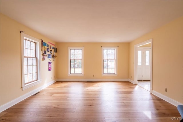 unfurnished room with visible vents, baseboards, and wood finished floors