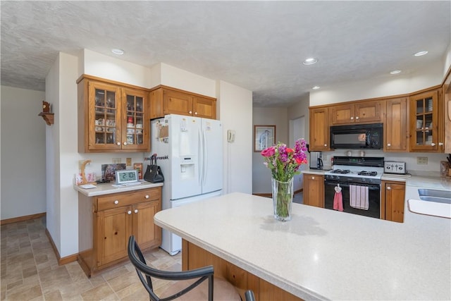 kitchen with range with gas stovetop, light countertops, white refrigerator with ice dispenser, and black microwave