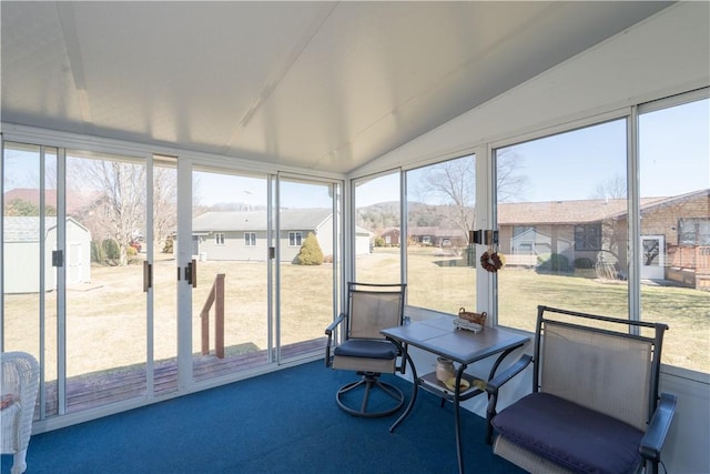 sunroom / solarium with a residential view, plenty of natural light, and vaulted ceiling