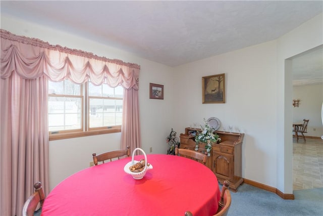 carpeted dining room with baseboards