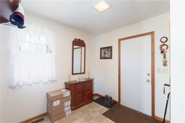 foyer featuring baseboards and visible vents