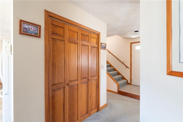 corridor with stairs, baseboards, and light carpet