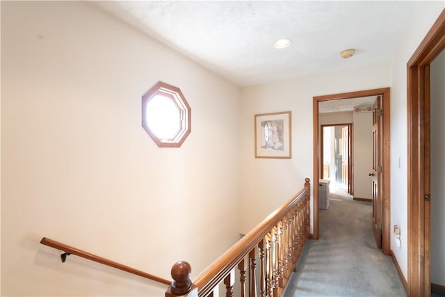 hallway with baseboards, an upstairs landing, and carpet