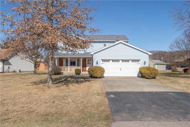 traditional-style home with covered porch, driveway, a front lawn, and a garage