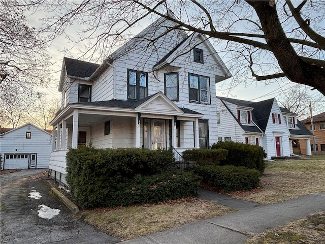 view of front of house featuring a garage, an outbuilding, driveway, and a shingled roof