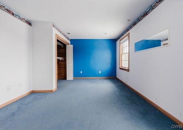 carpeted empty room featuring baseboards