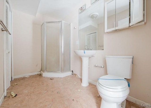 bathroom with toilet, a stall shower, a closet, tile patterned flooring, and baseboards